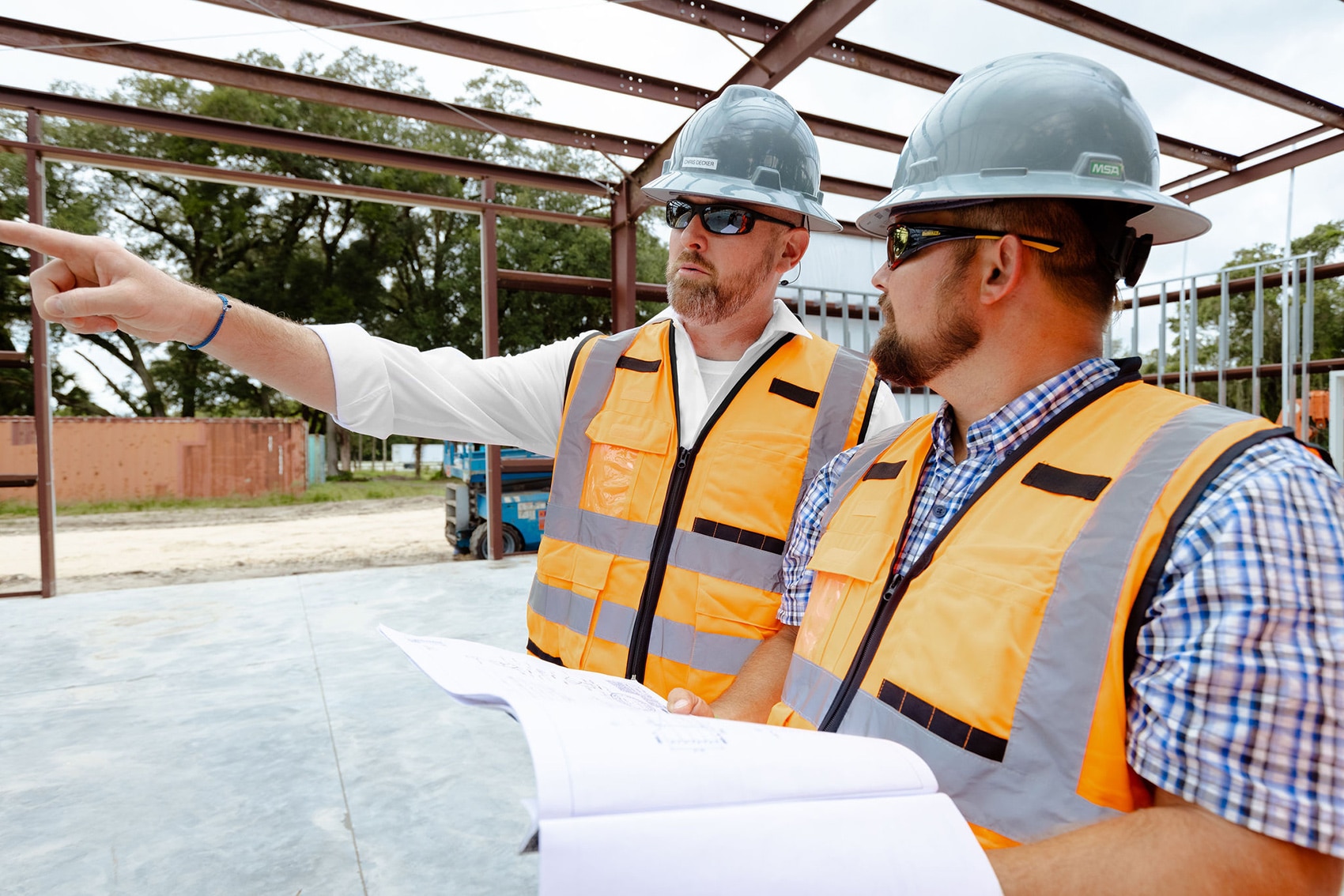 two construction workers with hard hats talking and pointing